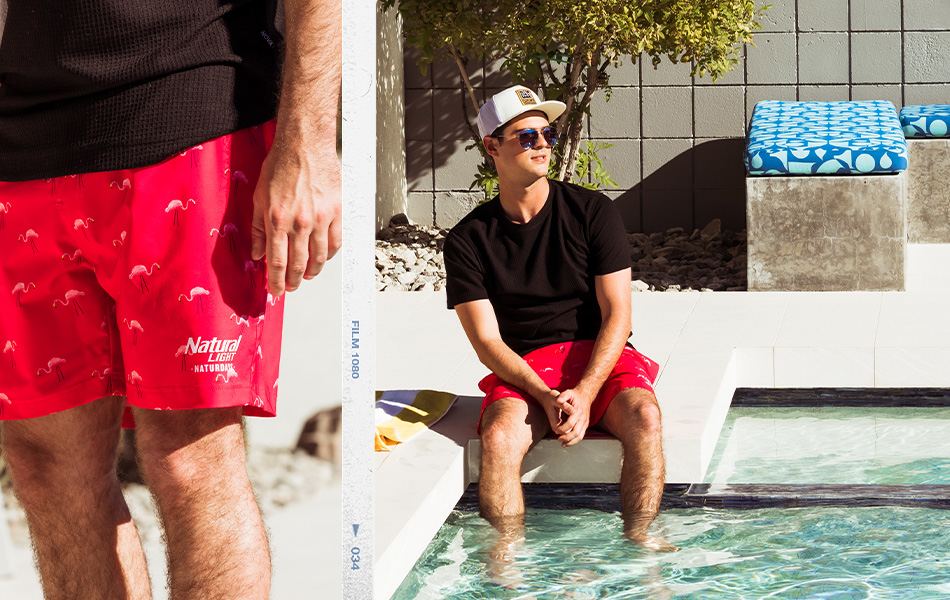 Men's Swimwear - A guy wearing a black t-shirt with a pair of red Natural Light printed swim trunks